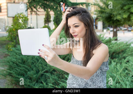 Giovane donna prendendo selfie con un dispositivo tablet pc Foto Stock