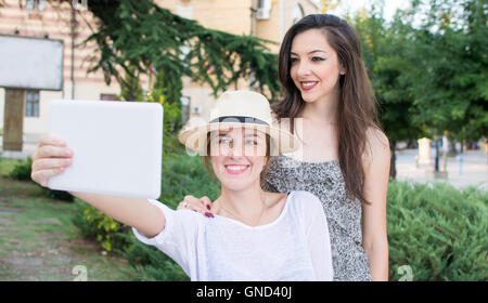 Due amiche tenendo selfie con una compressa Foto Stock