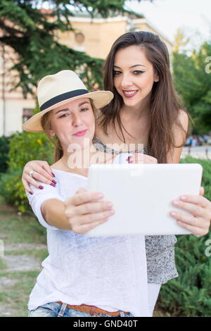 Due amiche tenendo selfie con una compressa Foto Stock