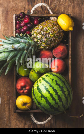 Estate frutta varietà nel vassoio in legno scuro su sfondo rustico Foto Stock