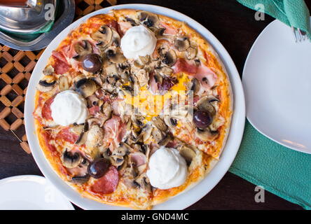 Round pizza servita su un piatto al ristorante Foto Stock