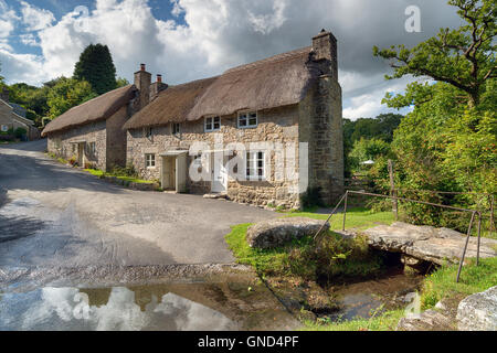 Splendido cottage con il tetto di paglia accanto a una Ford a Ponsworthy sul Parco Nazionale di Dartmoor in Devon Foto Stock