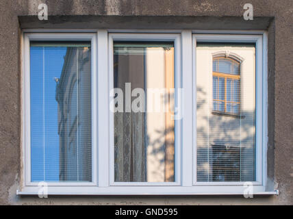 Nuove cornici bianche della finestra, riflettendo il vecchio edificio giallo e il blu del cielo. Foto Stock