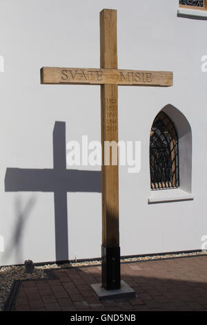 Croce di legno con anni di Saint missioni e la sua ombra sul muro della chiesa gotica in Svaty Jur, Slovacchia. Tradizionale Foto Stock