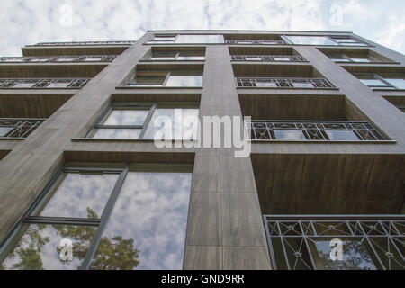 Edificio residenziale su sfondo cielo alberi e riflessioni in Windows Foto Stock