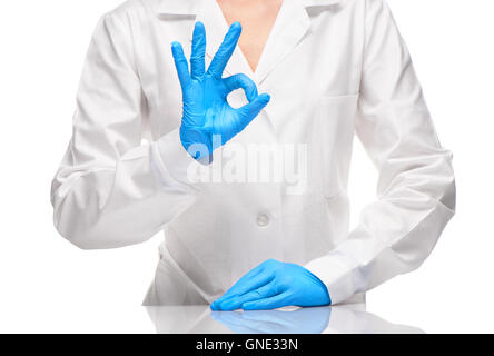 Close up medico donna in bianco camice blu e sterilizzare guanti chirurgici che mostra segno OK Foto Stock