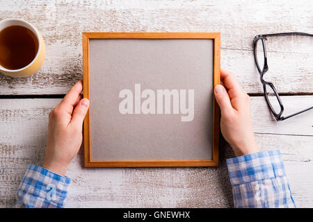 Irriconoscibile donna azienda empty picture frame, studio shot. Foto Stock