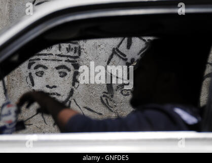 Sanaa, Yemen. Il 30 agosto, 2016. Un uomo yemenita rigidi passato un disegno di una vittima di sparizione forzata in una strada a Sanaa, Yemen, il 30 agosto 2016. Giornata internazionale delle vittime di sparizioni forzate è contrassegnata sul 30 agosto di ogni anno. © Hani Ali/Xinhua/Alamy Live News Foto Stock