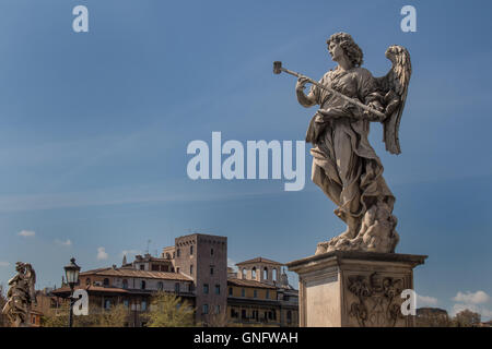 Vicino al castello di Roma, vi è in piedi su un ponte la statua di un angelo. Edifici residenziali in background. Cielo blu Foto Stock