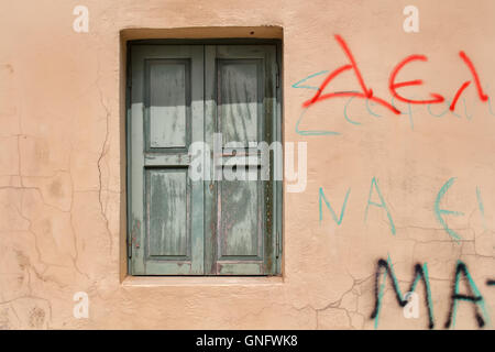 Orange facciata della casa con una finestra con un otturatore verde. Poche le lettere graffiti sulla facciata. Foto Stock