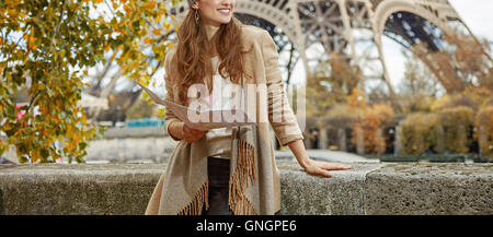 Fughe d'autunno a Parigi. sorridente giovane donna turistica sul terrapieno vicino alla Torre Eiffel a Parigi, Francia azienda mappa e guardando a parte Foto Stock