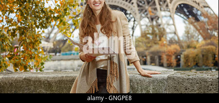 Fughe d'autunno a Parigi. sorridente giovane donna turistica sul terrapieno in Paris, France holding mappa e guardando in lontananza Foto Stock