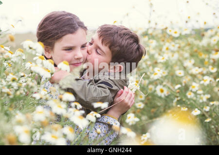 Ragazzo baciare una ragazza sua guancia nel campo delle margherite, Andalusia, Spagna