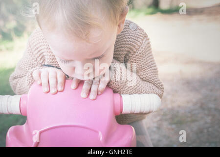 Ragazzo seduto su una bicicletta giocattolo Foto Stock