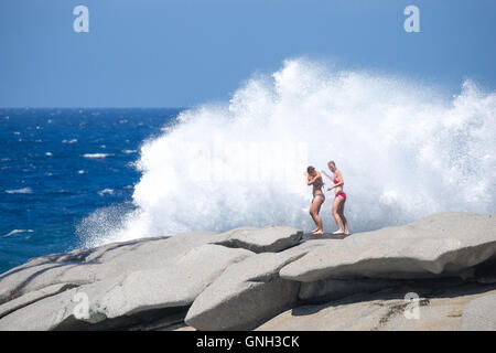 Due donne in piedi sulle rocce colpito dalla grande onda, Corsica, Francia Foto Stock