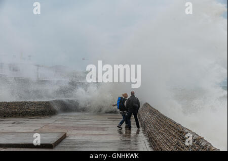 Un paio di eseguire per sfuggire le onde sul lungomare di Brighton Foto Stock