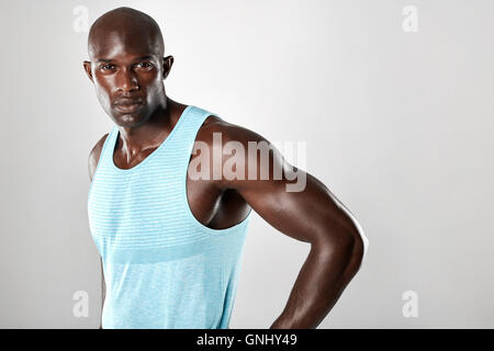 Ritratto di montare giovane con costituzione muscolare in piedi contro uno sfondo grigio. Afro Americano modello di fitness. Foto Stock