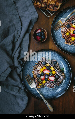 Due piastre di brioche cialde sono condito con frutta e spolverato con zucchero a velo fotografata dalla vista dall'alto. Foto Stock