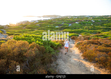 Giovane donna che corre lungo un sentiero, Corsica, Francia Foto Stock