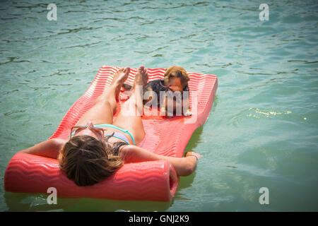 Donna sdraiata sulla floating materasso Materasso per piscina con cane beagle Foto Stock