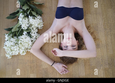 Vista panoramica di una ragazza che si trova sul pavimento con un mazzo di fiori Foto Stock