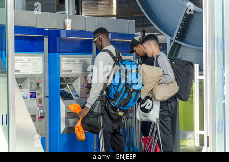 Persone che acquistano biglietti ferroviari da un self-service ticket machine. Foto Stock