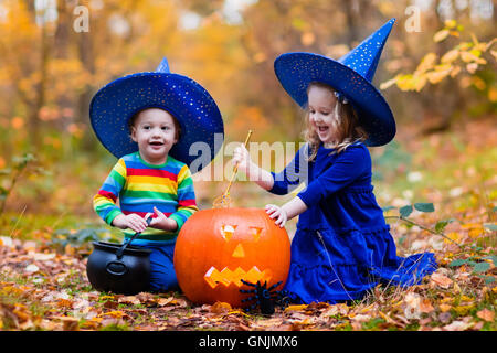 Bambini indossare blu costumi strega con cappelli giocando con zucca e ragno in autunno Park di Halloween. Kids dolcetto o scherzetto. Foto Stock