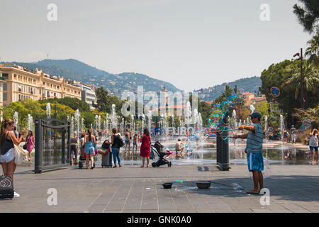 Nizza, Francia - luglio 2016: persone e un uomo compiendo enormi bolle di sapone sulla piazza principale di Nizza, Francia mentre i bambini giocano in th Foto Stock