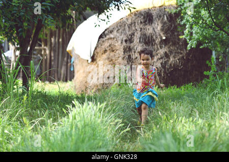 Felice bambina che corre lungo un percorso di avvolgimento nella campagna al tramonto Foto Stock