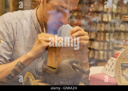 Toledo, Spagna - 28 Luglio 2016: goldsmith lavorando su damascene pezzo attraverso la vetrina del negozio nel centro storico di Toledo, Spai Foto Stock