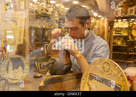 Toledo, Spagna - 28 Luglio 2016: goldsmith lavorando su damascene pezzo attraverso la vetrina del negozio nel centro storico di Toledo, Spai Foto Stock