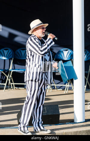 Broadstairs Settimana della Musica Folk Festival. Presenter, annunciatore, Mick Scott indossando un cappello di paglia e strisce in bianco e nero, suit parlando nel microfono. Foto Stock