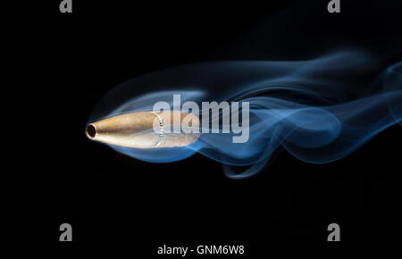 Color bronzo bullet con fumo dietro su sfondo nero Foto Stock