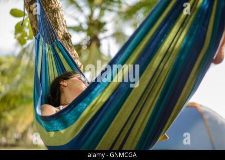 Donna prendendo un pisolino su una amaca in spiaggia Foto Stock