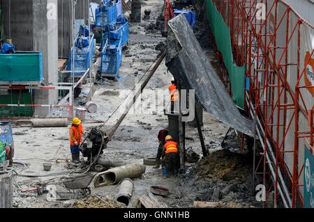 Lavoratori edili al wet sito di costruzione con i ponteggi e gli strumenti inclusi machine Bangkok in Thailandia Foto Stock