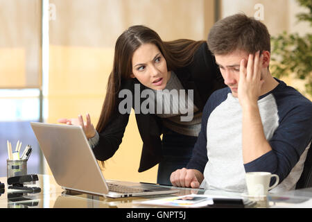 Boss scolding una vergognosa dipendente al lavoro in un ufficio Foto Stock