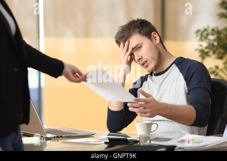 Preoccupato per il tirocinante riceve una notifica di respingere o di cattive notizie dal suo capo o un compagno seduto in un desktop in ufficio Foto Stock