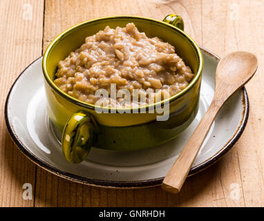 Sano e naturale di farina di avena in verde ciotola sul tavolo di legno Foto Stock