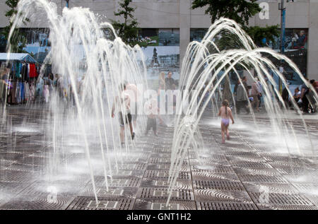 Caldo giorno d'estate quando i bambini hanno giocato per ore in acqua a impulsi jet fontane della piazza di Williamson, mentre i genitori si godeva di un drink al sole. La meravigliosa danza di getti di acqua sono ora in funzione nel centro della citta'. Liverpool, Merseyside, Regno Unito Foto Stock