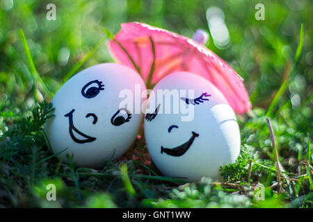 Uova divertente imitando felice coppia di amanti con volti sorridenti sotto ombrellone Foto Stock