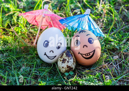 Uova divertente imitando sorridenti coppia mista bianca e colorata con i genitori versicolored baby sotto ombrellone Foto Stock