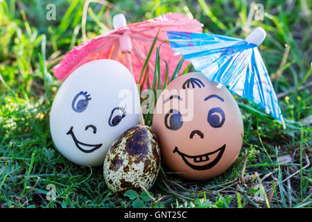 Uova divertente imitando sorridenti coppia mista bianca e colorata con i genitori versicolored baby sotto ombrellone Foto Stock