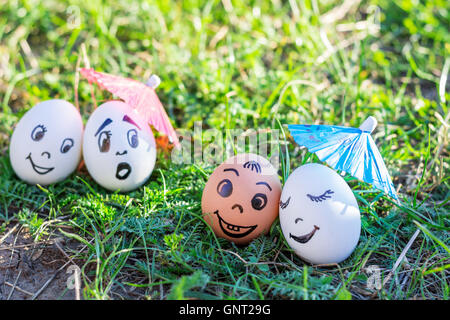 Funny uova sotto gli ombrelloni imitando felice coppia mista e indignato bianco giovane Foto Stock