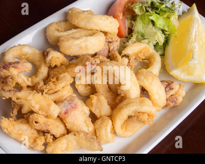 Calamari fritti su una piastra con insalata di pomodoro e limone. Malaga, Costa del Sol, Andalusia Spagna. Europa Foto Stock