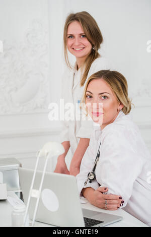 Due femmina friendly allegro medici o infermieri isolato in ufficio sorridente e guardando la fotocamera Foto Stock