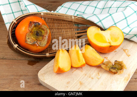 Persimmon colore giallo maturi frutti diviso sulla tavola di legno Foto Stock