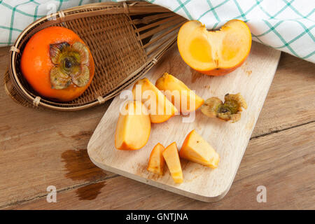 Persimmon colore giallo maturi frutti diviso sulla tavola di legno Foto Stock