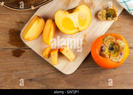 Persimmon colore giallo maturi frutti diviso sulla tavola di legno Foto Stock