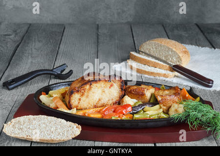 Maiale fritto con le verdure e le erbe in una padella in ghisa. Foto Stock