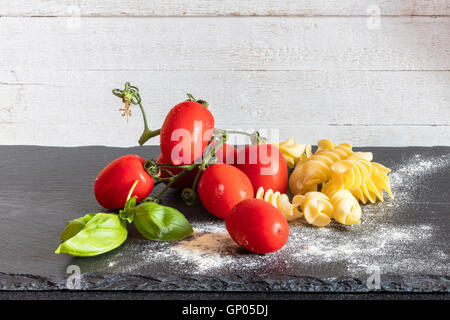 Fusilli pomodoro fresco e basilico gli ingredienti per un piatto tipico di pasta italiana Foto Stock